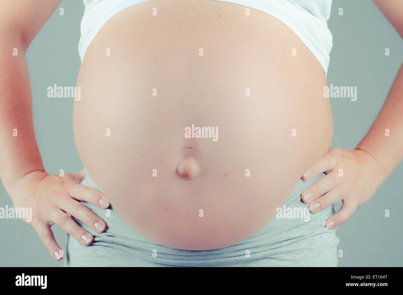 pregnant woman on black background with hands on her belly Stock Photo