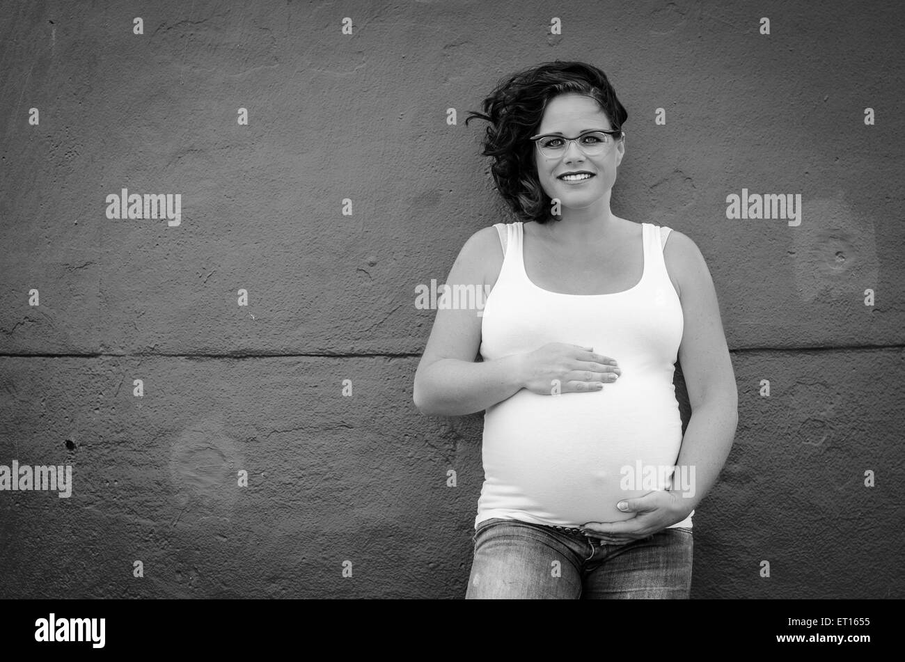 pregnant woman in front of a wall in urbex situation Stock Photo