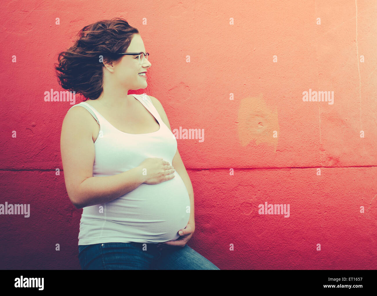 pregnant woman in front of a wall in urbex situation Stock Photo