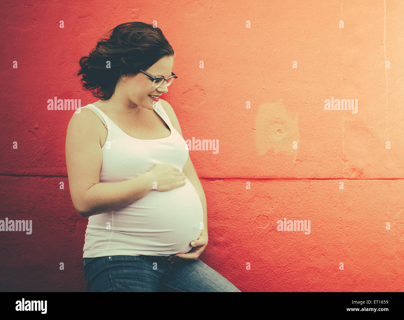 pregnant woman in front of a wall in urbex situation Stock Photo