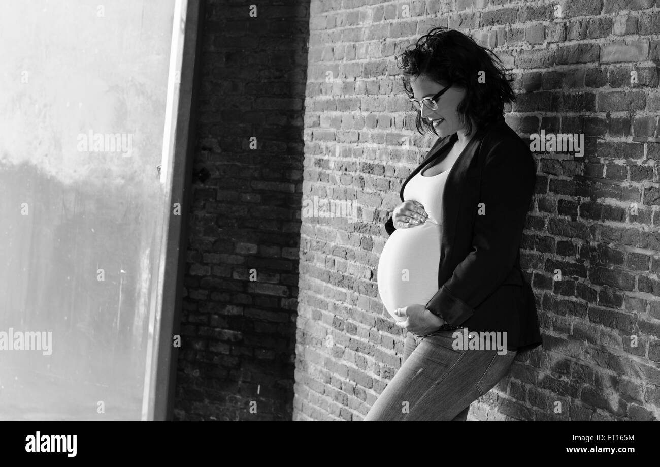 pregnant woman in front of a wall in urbex situation Stock Photo