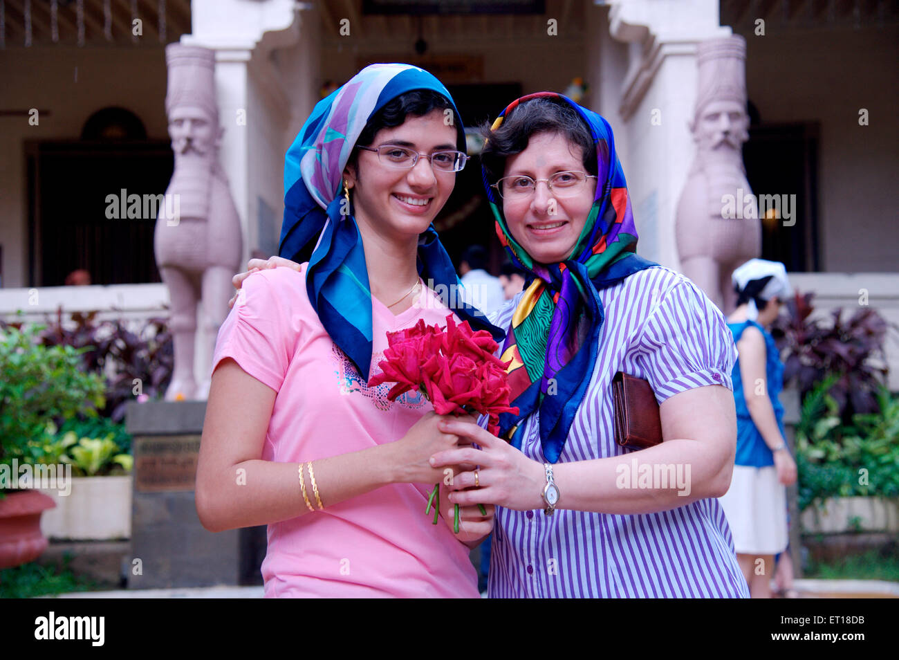 Women mother and daughter exchanging flowers celebrating Parsi New Year in Fire Temple Mumbai India - MR#784L & 364 - RMM 179732 Stock Photo