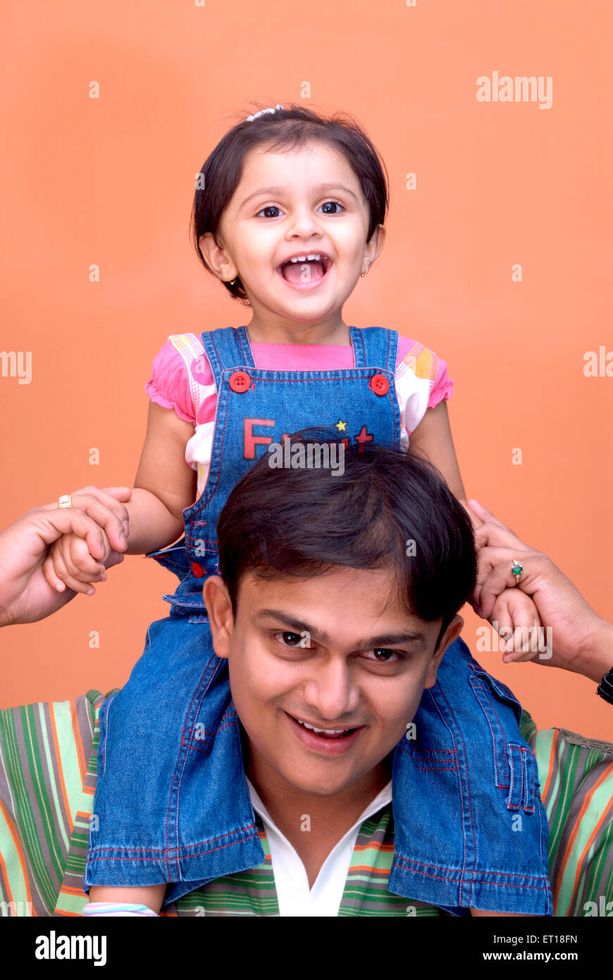 Baby daughter sitting on shoulder of man father holding hands India - MR#364 Stock Photo