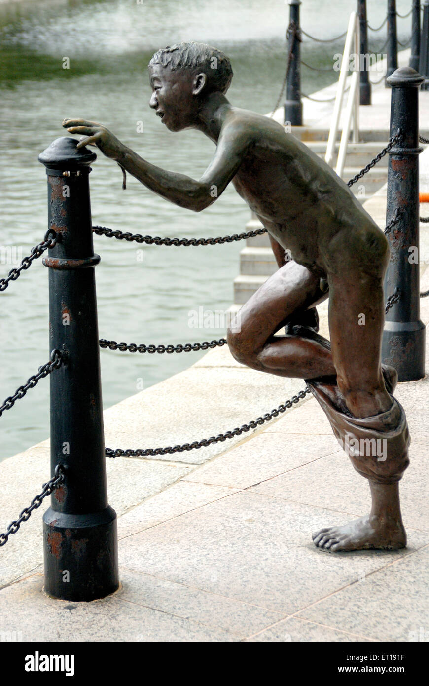 Statue of bronze boy ready to jump in water near Suntec city ; Singapore Stock Photo
