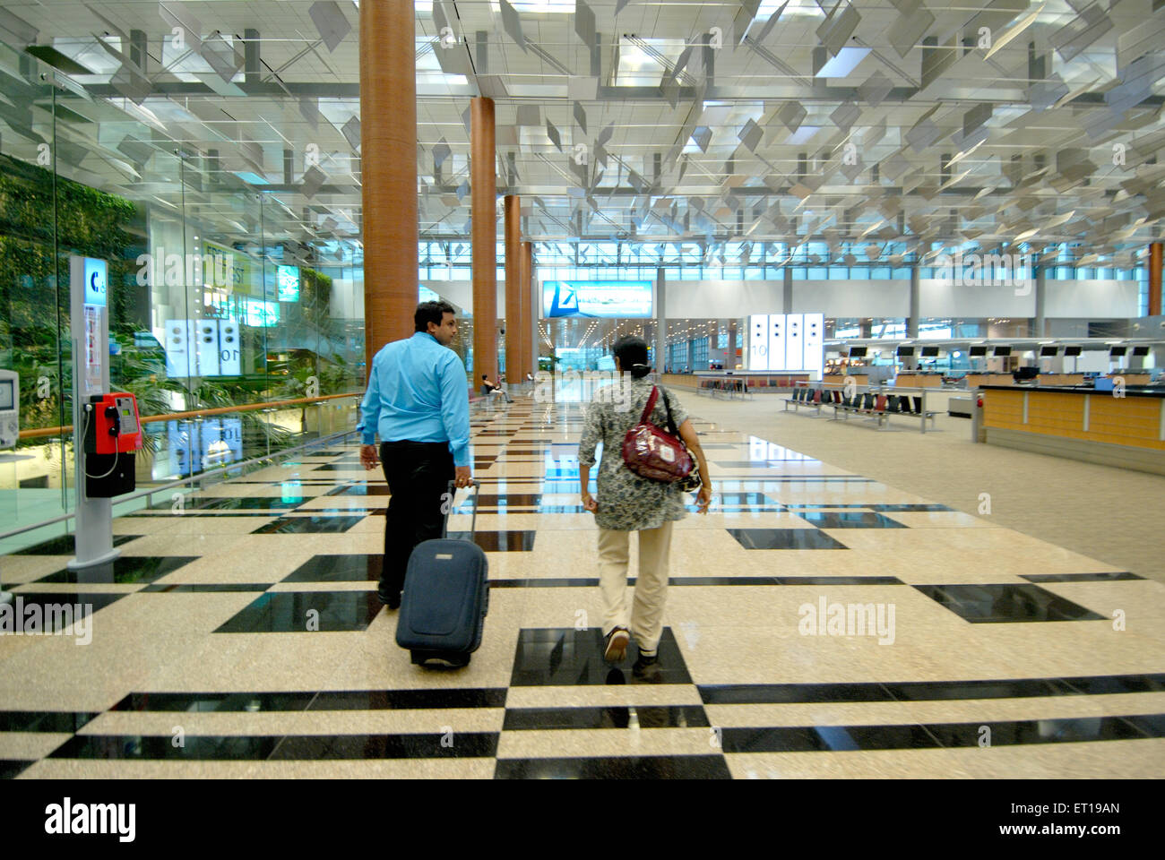 Couple with strolley luggage inside Changi airport terminal Singapore - MR#364 Stock Photo