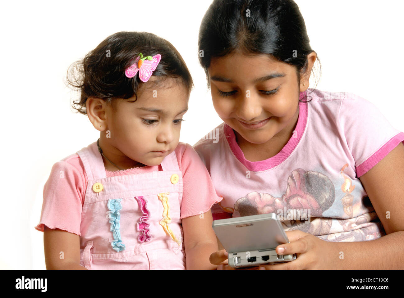 Two Indian sisters playing digital game on mobile phone - MR#736L & 152 - RMM 167206 Stock Photo