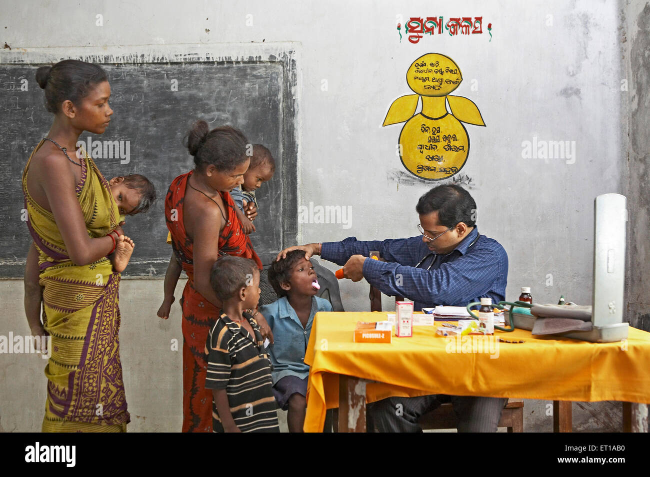 Medical doctor examining health of poor village boy at health check up camp initiative started by NGO Chinmaya Organization India Asia Stock Photo