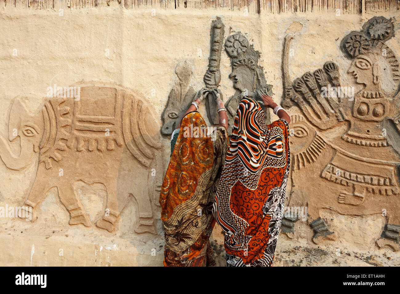 Women creating mud relief wall art mural sculpture ; Jitwarpur