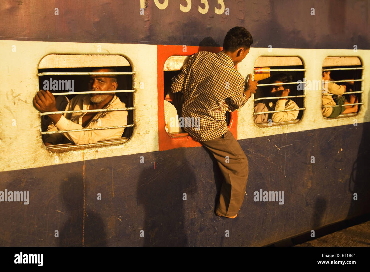 Man coming out from emergency window of train ; Surat railway station ; Gujarat  ; India ; Asia Stock Photo