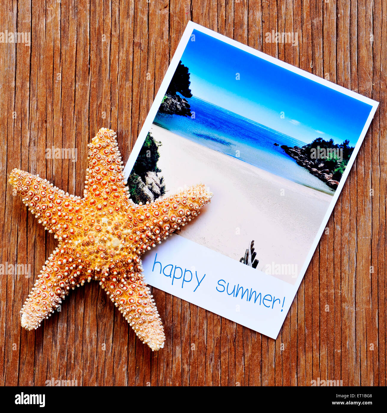 high-angle shot of a starfish and an instant photo of a peaceful beach with the text happy summer written in its frame, placed o Stock Photo