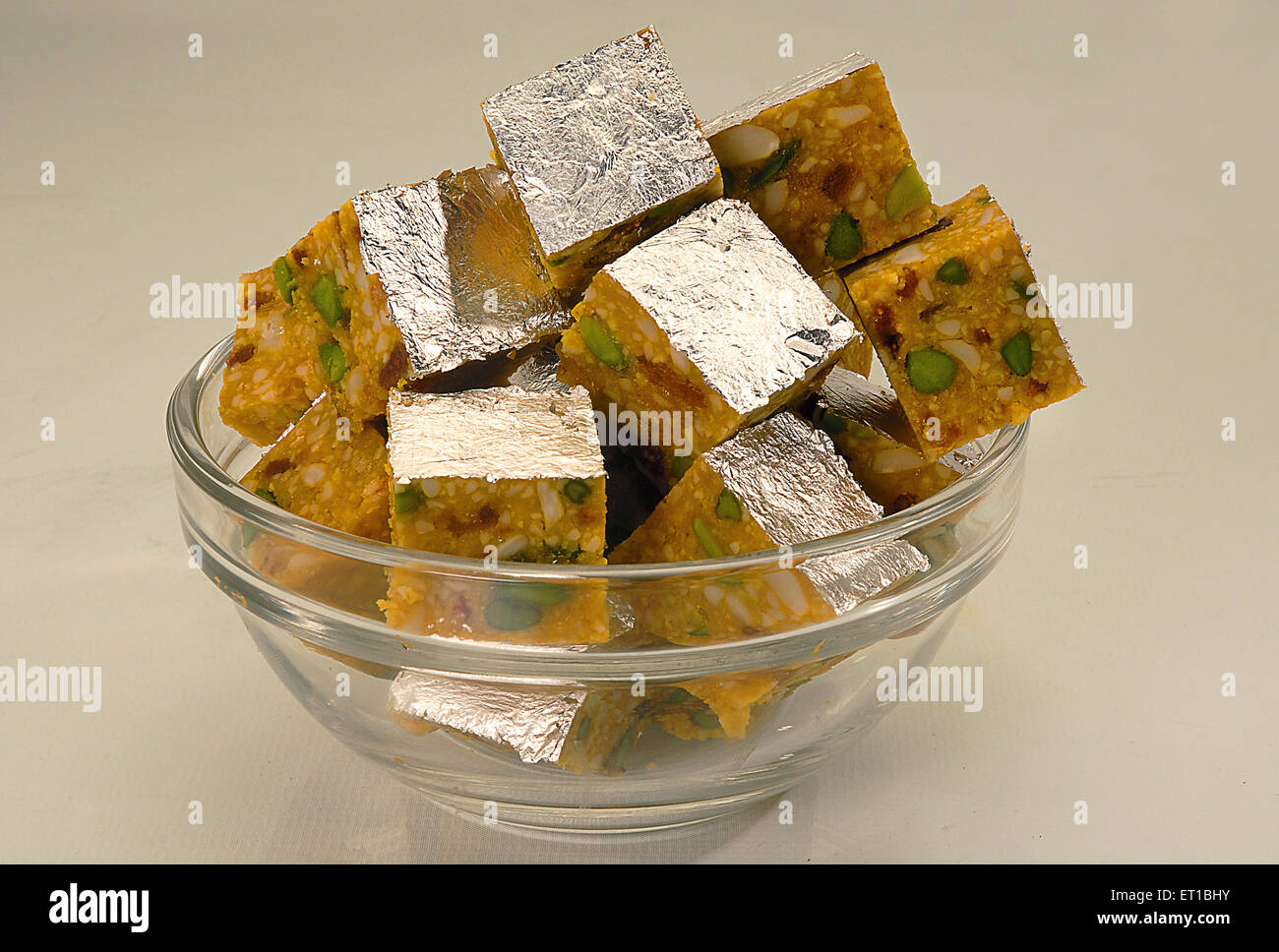 Indian sweet panchmeva chakki with silver leaf varakh in bowl on white background Jodhpur Rajasthan India Stock Photo