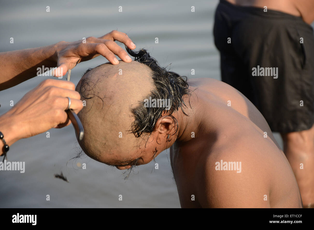 barber cutting hair on Varanasi Ghat Uttar Pradesh India Stock Photo