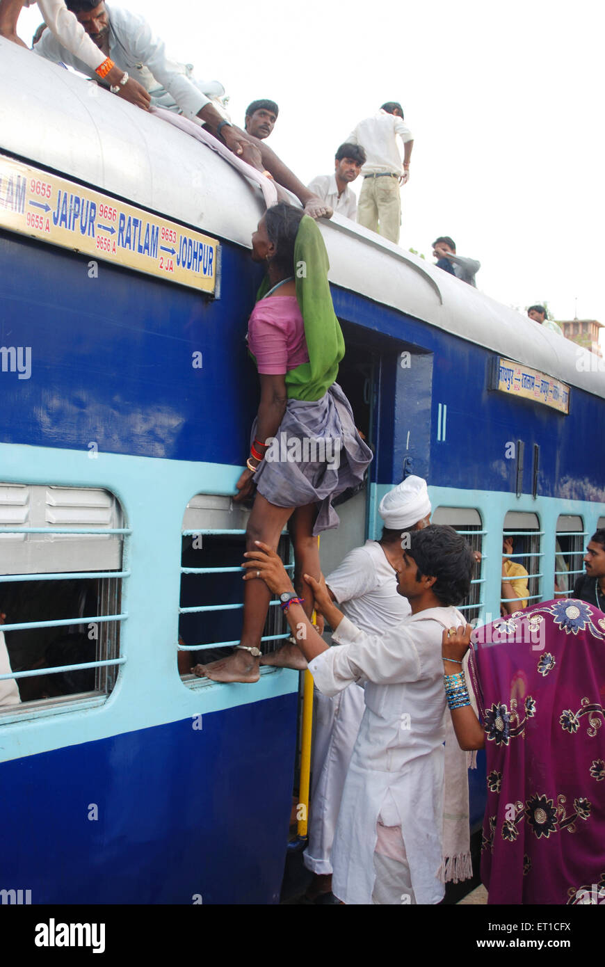 Men dragging woman up trying to climb on roof of train at Jodhpur station Rajasthan India Stock Photo