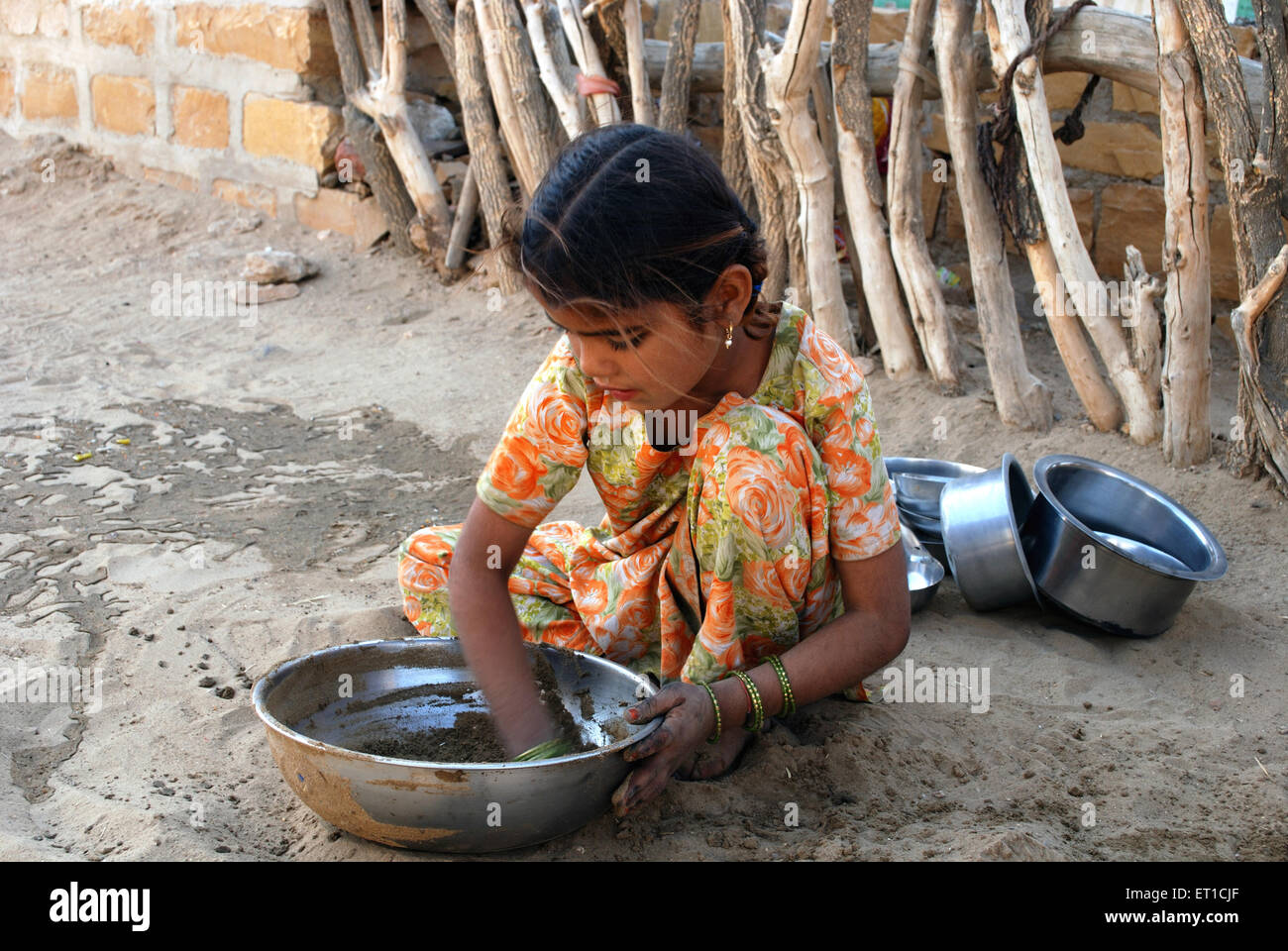 Girl cleaning utensil ; Khuri ; Khuhri ; Jaisalmer ; Rajasthan ; India Stock Photo