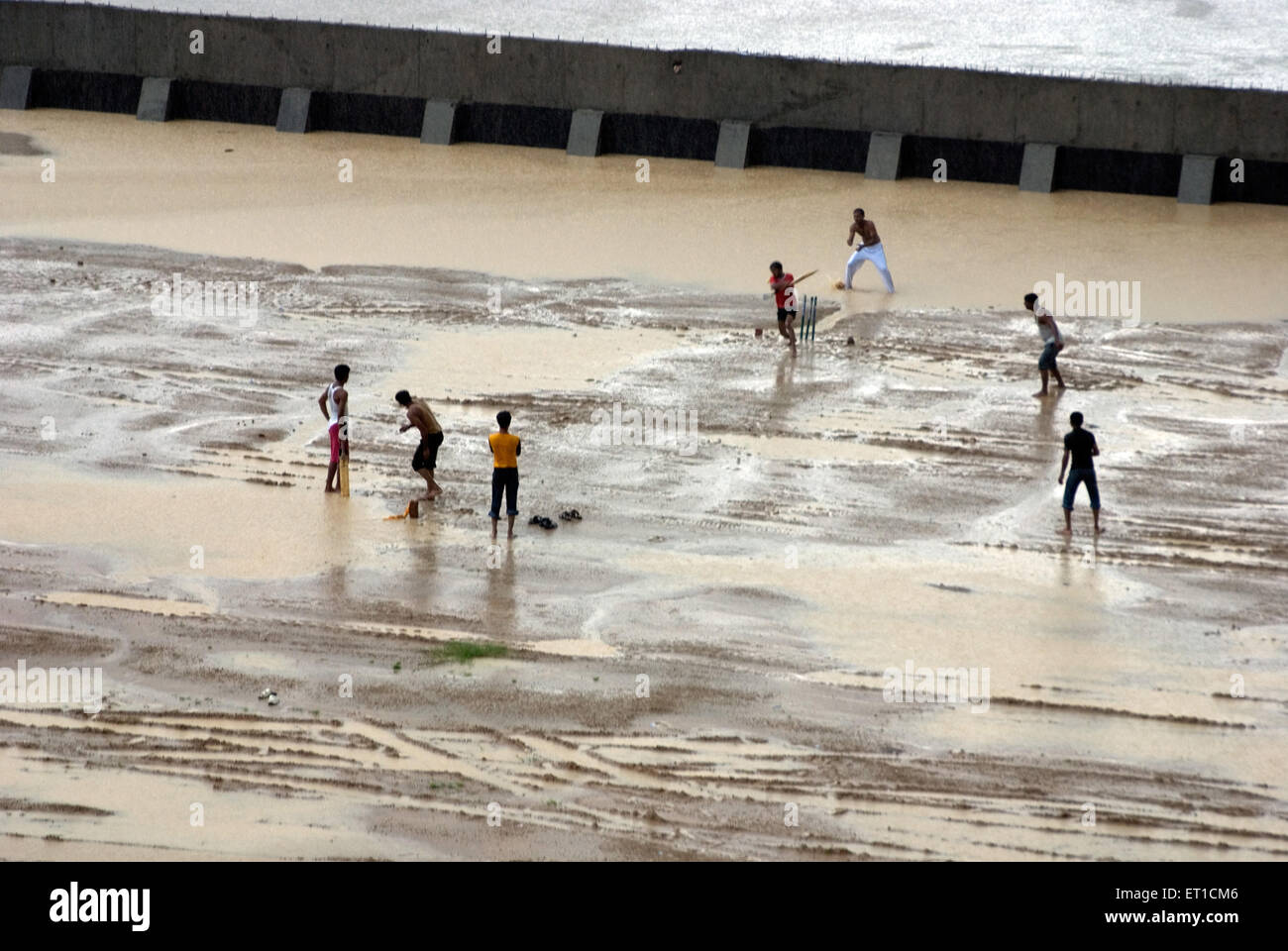 Boys playing cricket at sabarmati river in monsoon ; Ahmedabad ; Gujarat ; India Stock Photo