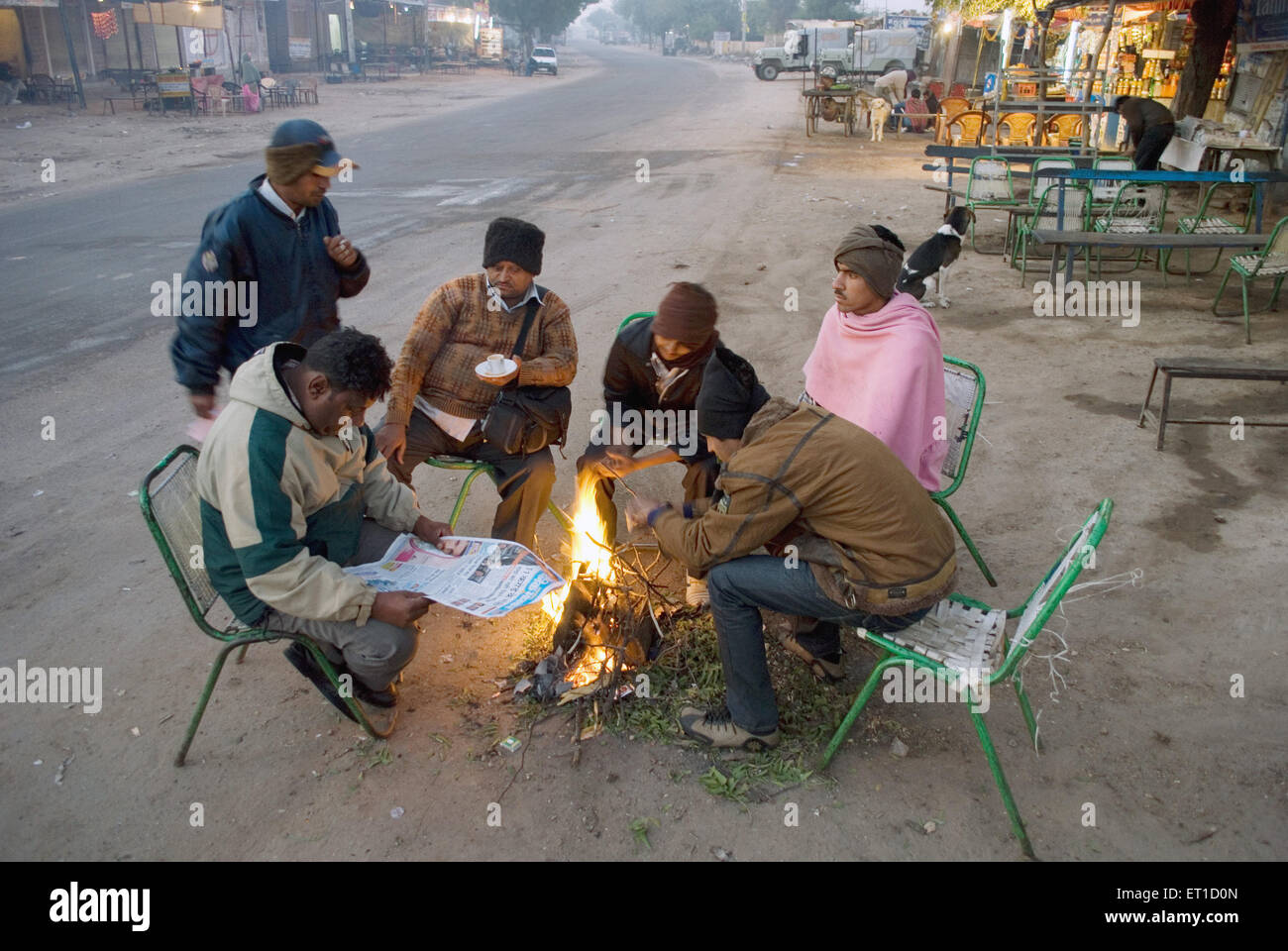 People warming up fire at bus stop ; Jodhpur ; Rajasthan ; India NOMR Stock Photo