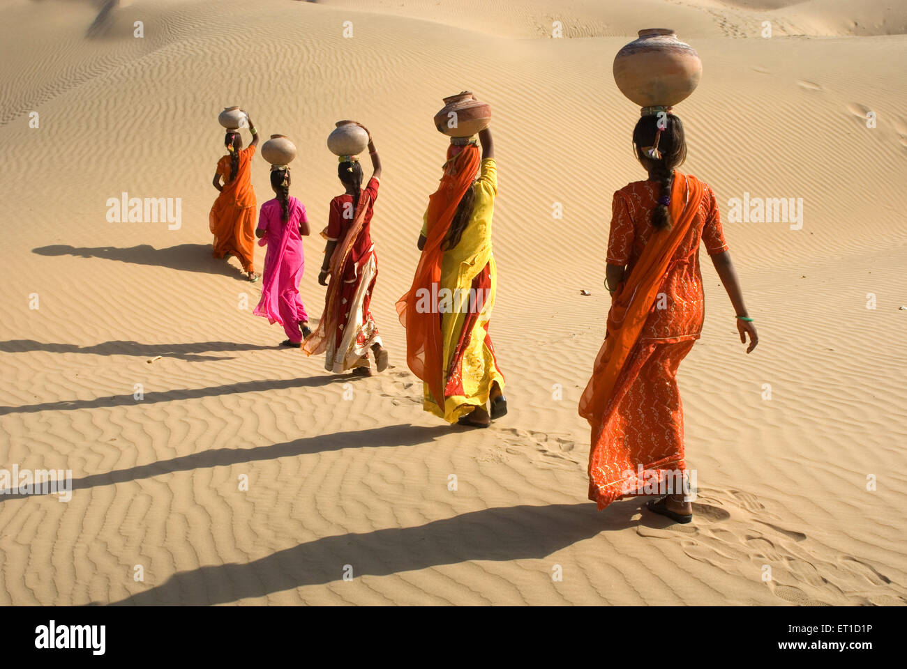 Five Indian women with earthen pots balancing on head walking in Thar desert , Khuhri , Jaisalmer , Rajasthan , India , Asia Stock Photo