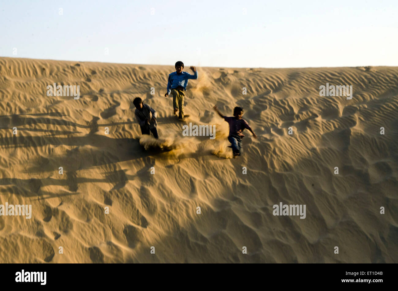 Boys for Fun Running Down on Sand Dune of Khuhri Jaisalmer Rajasthan India Asia Stock Photo