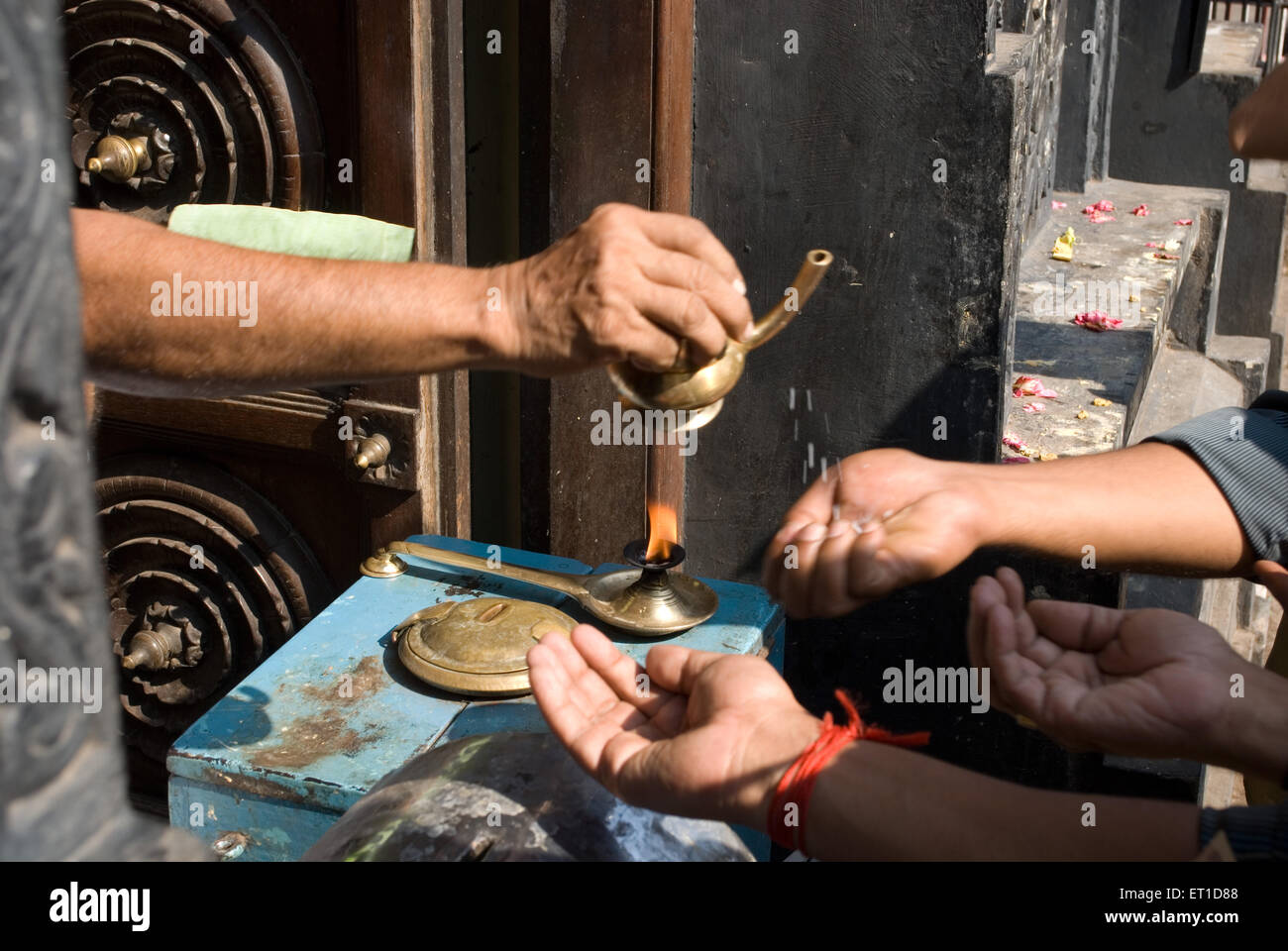 Priest pouring charnaamrita on the hands of devotees ; Trivandram ; Kerala ; India Stock Photo
