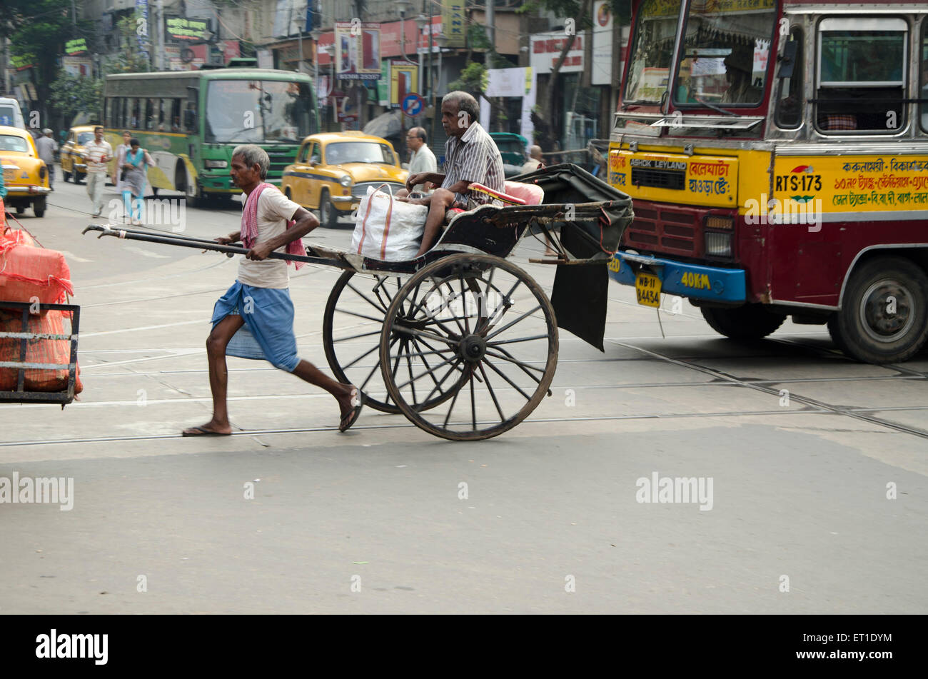 man crossing with pulling hand rickshaw Kolkata West Bengal India Asia Stock Photo