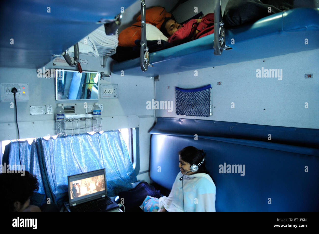 Passengers watching movie on laptop inside train ; India MR#400 Stock Photo