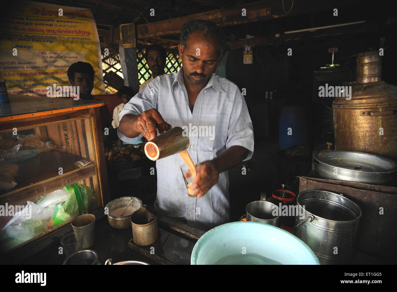 Man pouring tea in glass in tea shop ; Tanjore ; Thanjavur ; Tamil Nadu ; India Stock Photo