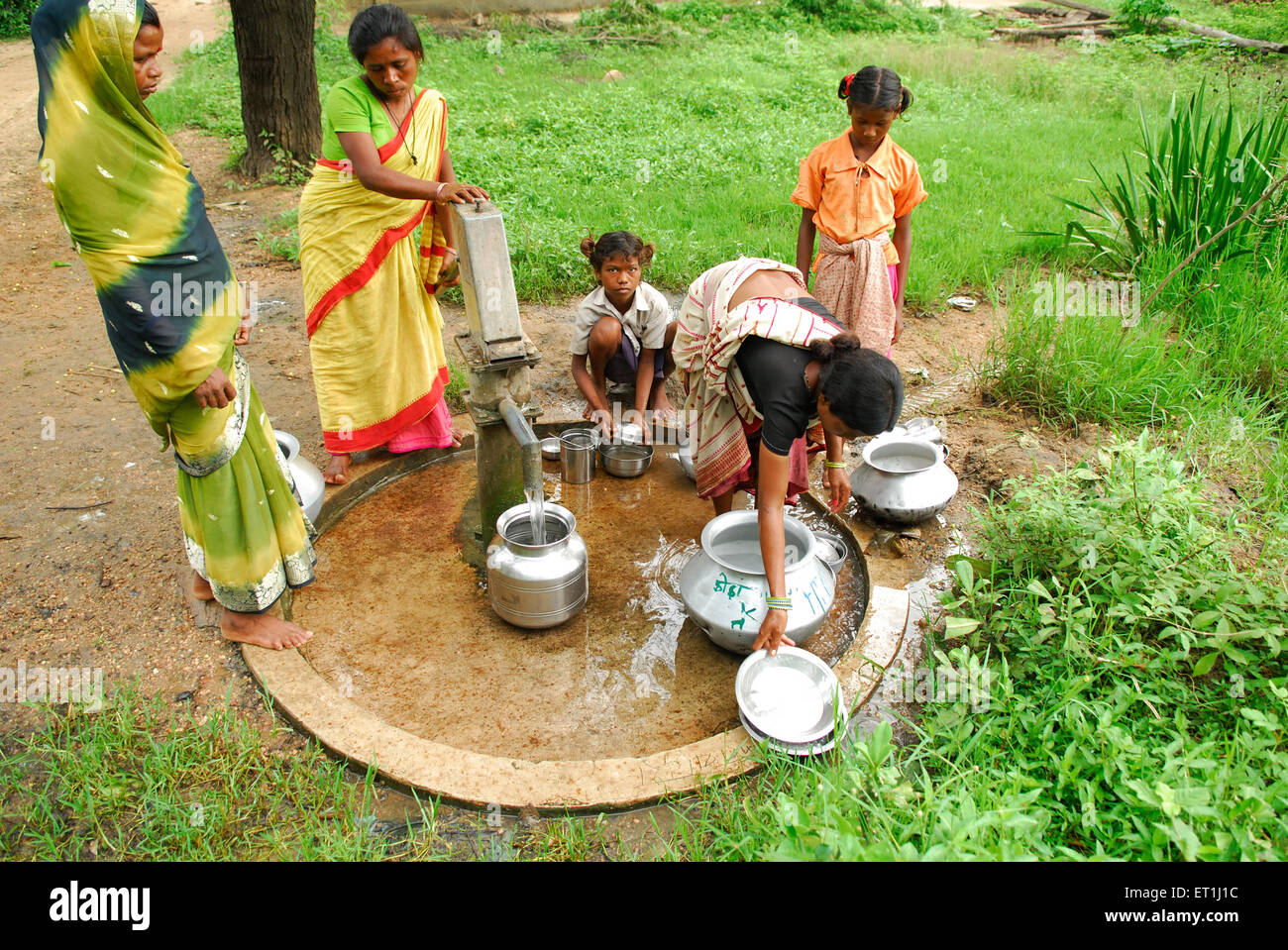 Ho tribes women filling pots with water by handpump ; Chakradharpur ; Jharkhand ; India NO MR Stock Photo