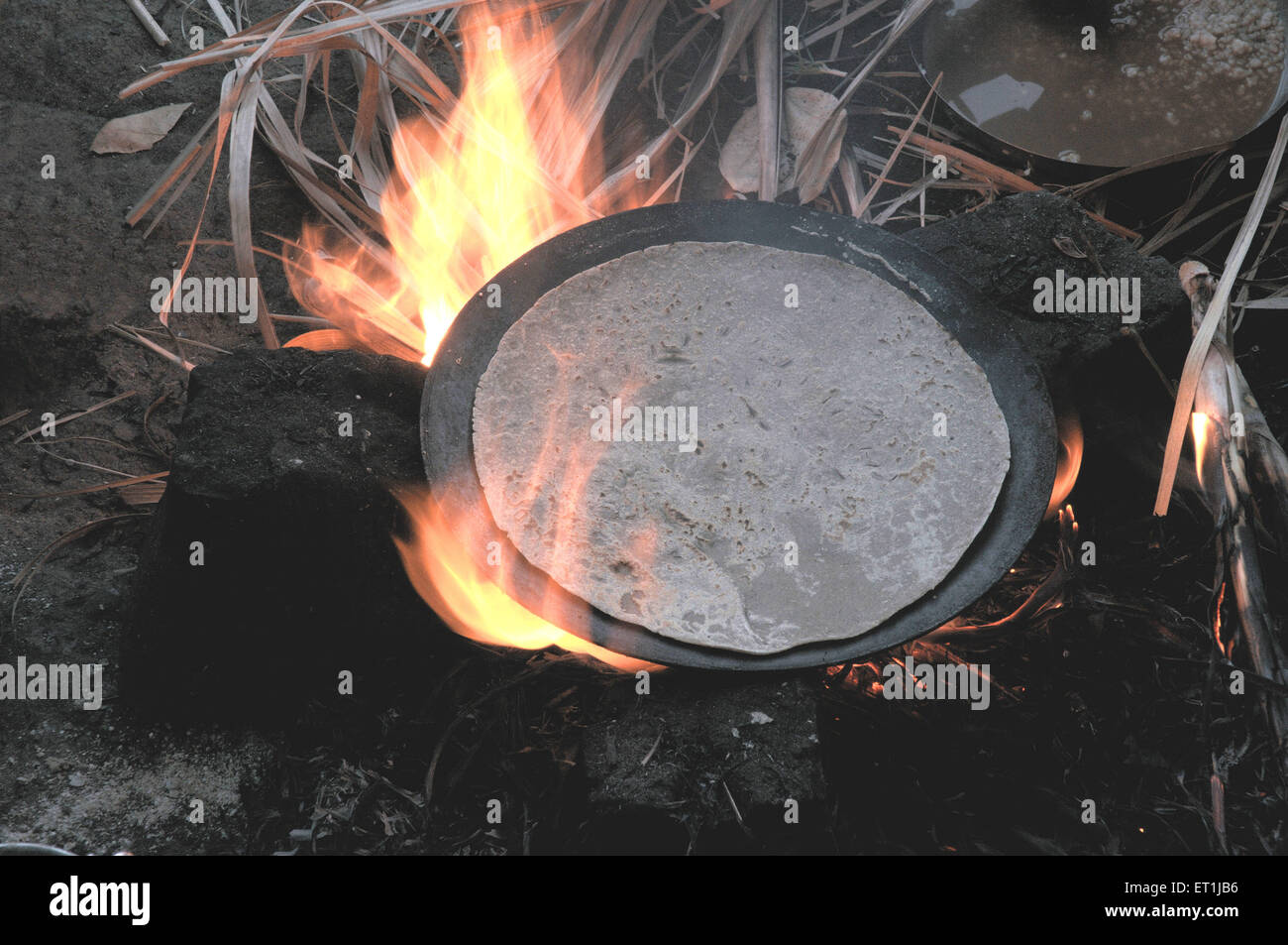 Roti making bread roasting cooking pan wood fired open village kitchen India Stock Photo