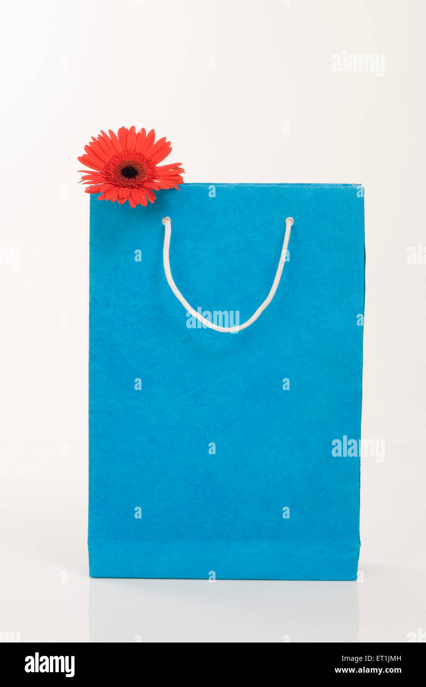 blue paper shopping bag with red gerbara flower Stock Photo