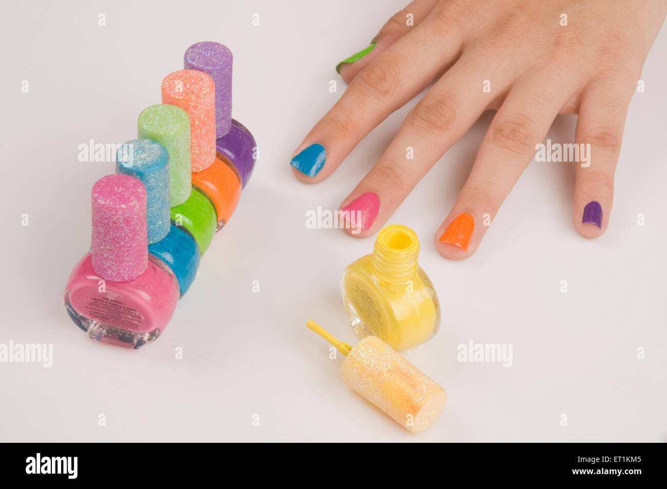 fingers with different colors nail polish bottles Stock Photo
