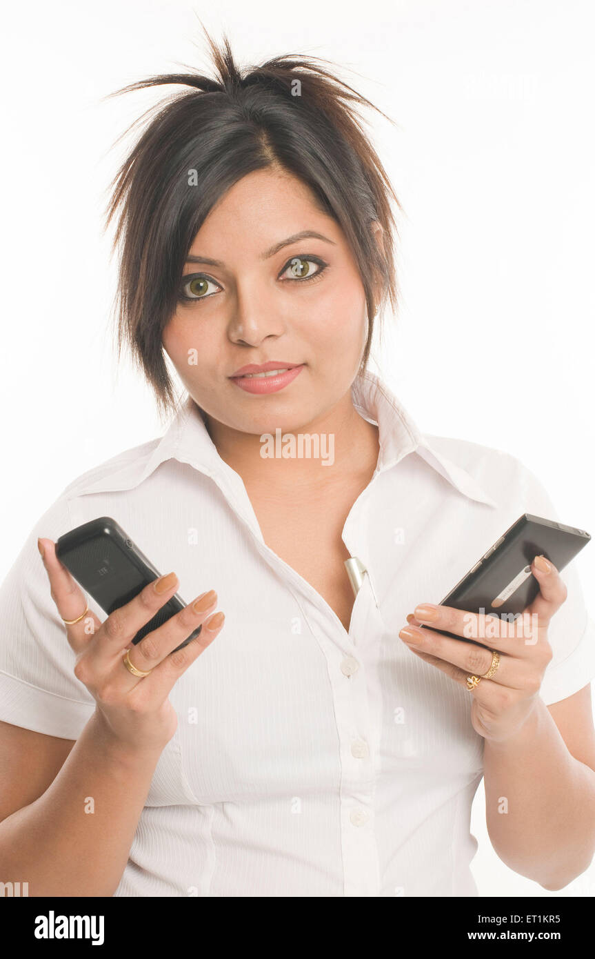 girl holding mobile phones Pune Maharashtra India Asia MR#686X Stock Photo