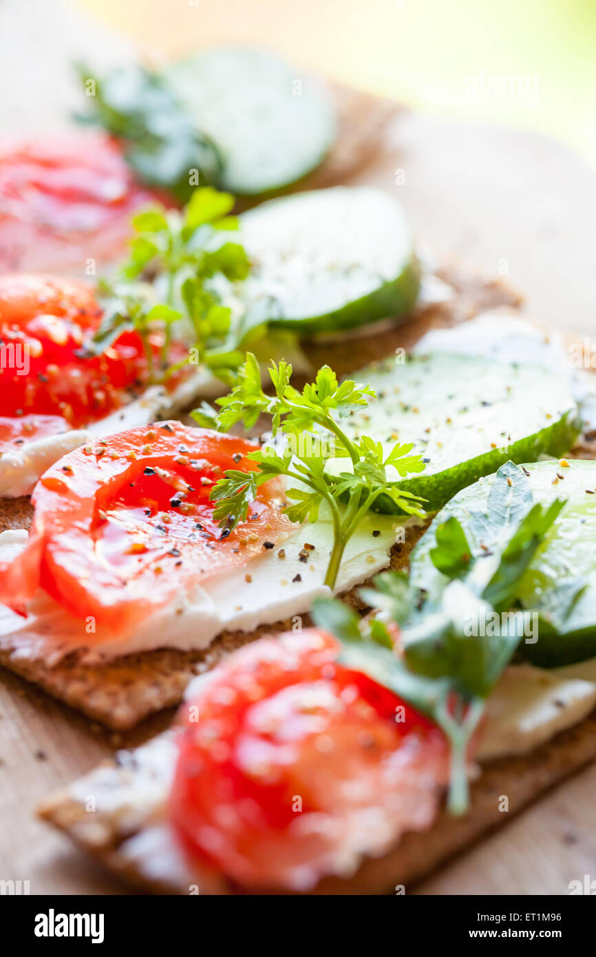 Healthy food. Sandwiches made of Finnish rye crisp bread, soft cheese, cucumber, tomato, parsley and black pepper Stock Photo
