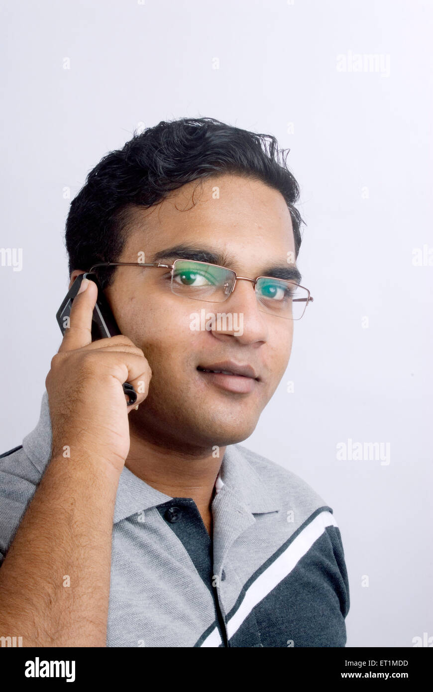 Young man using a mobile phone and smiling ; India MR#556 Stock Photo