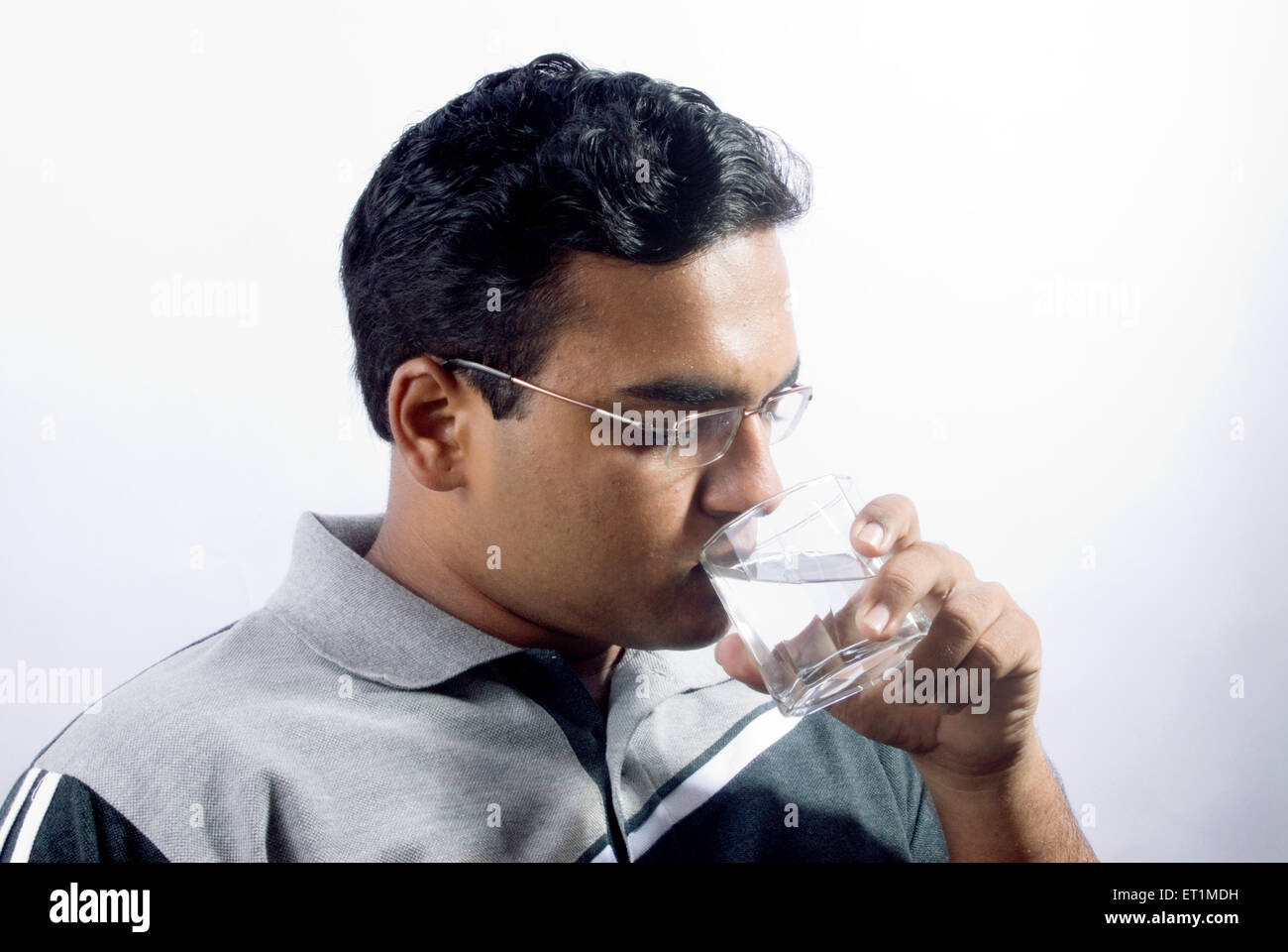 Young man drinking water from glass ; India MR#556 Stock Photo