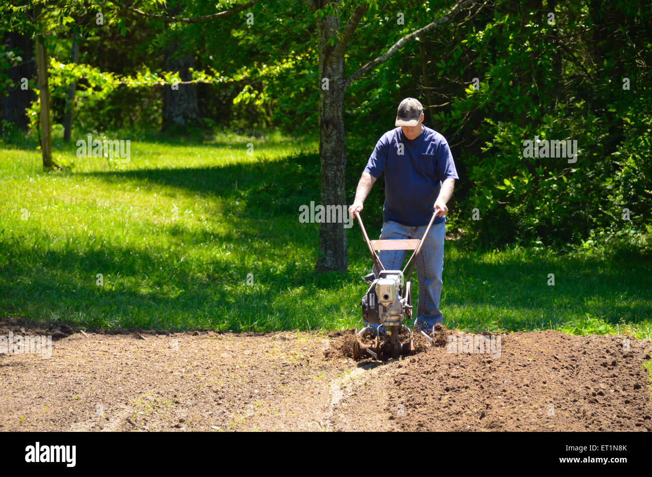 Man using a rototiller to prepare the soil. Stock Photo
