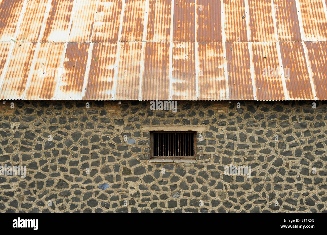 Stone wall with window and rusted metal roof ; Akluj ; Solapur ; Maharashtra ; India Stock Photo