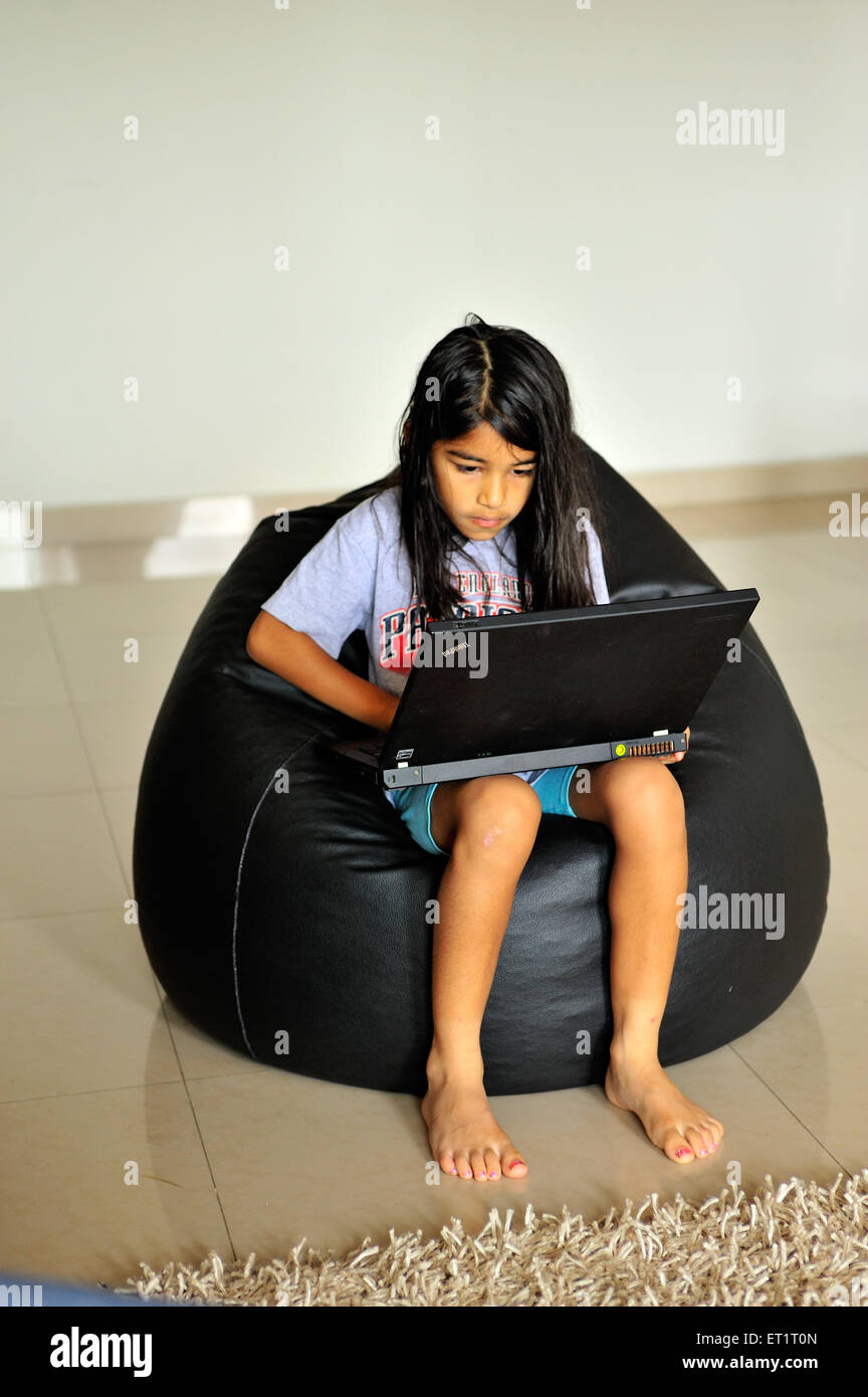 girl child working on laptop computer sitting on beanbag MR#556 Stock Photo
