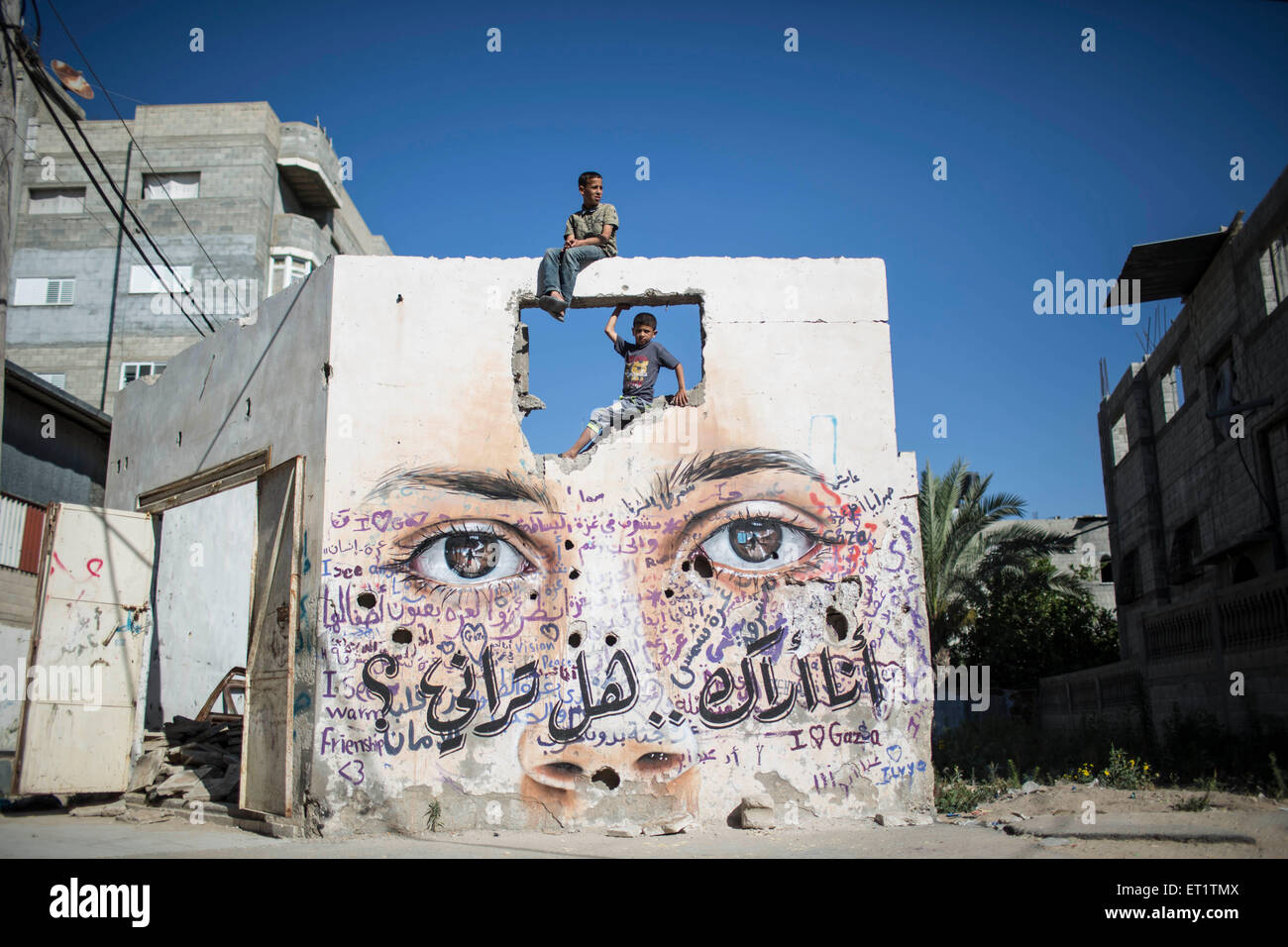 Gaza Strip. 10th June, 2015. Palestinian boys play over a wall painted with a mural by German artist Akot on the walls of houses destroyed during the 50-day Israeli offensive on the Gaza Strip in last July and August in Gaza City on June 10, 2015. © Wissam Nassar/Xinhua/Alamy Live News Stock Photo