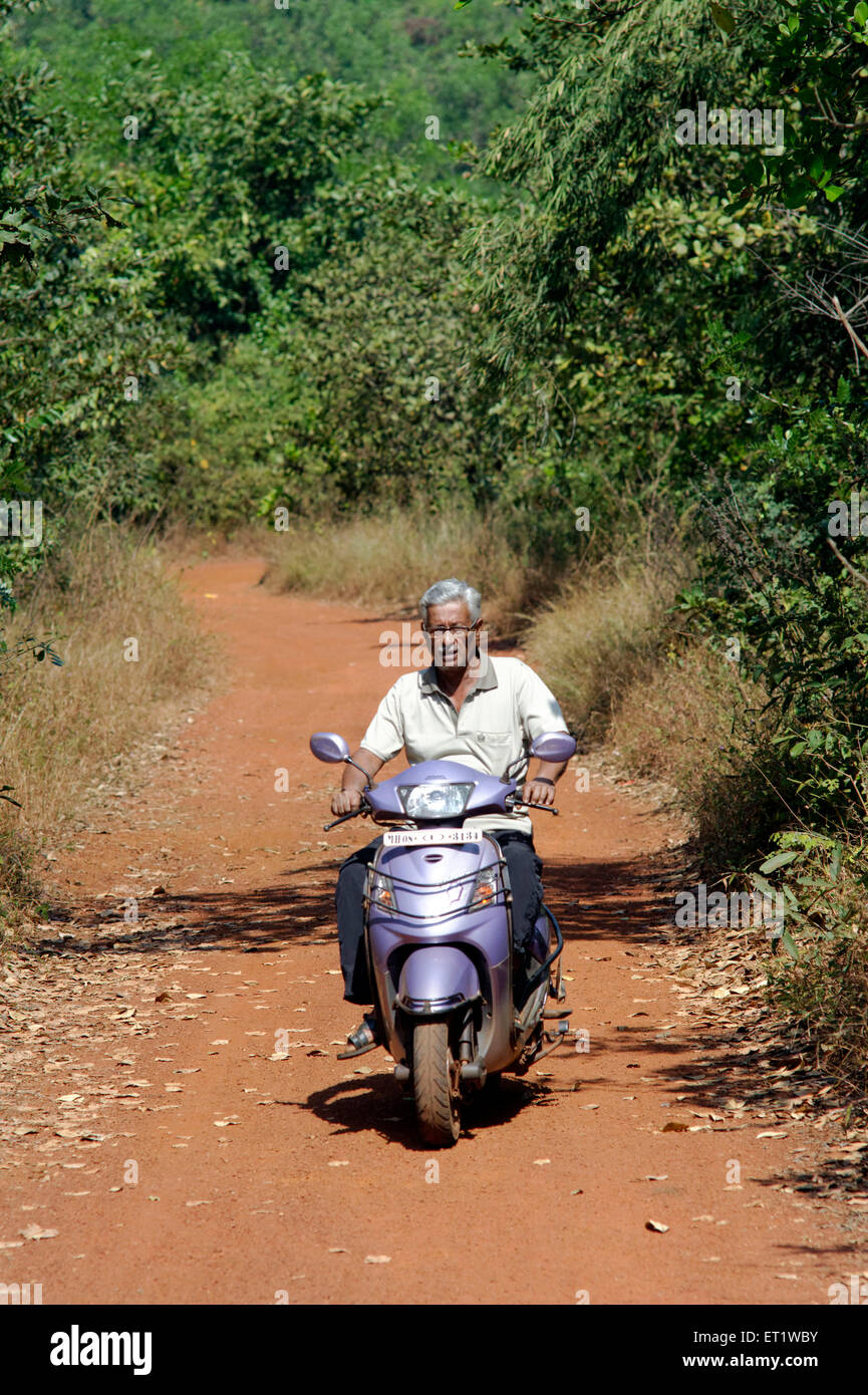Man on Scooter and Red Soil Road Konkan Maharashtra India MR#556 Stock Photo