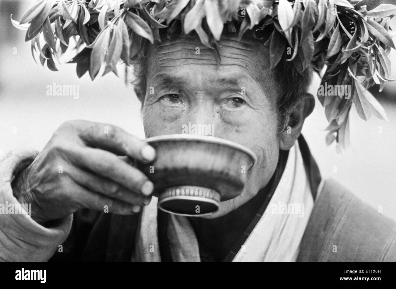 Bhutanese man drinks liquor out of an ornamental copper bowl ; Paro ; Bhutan Stock Photo