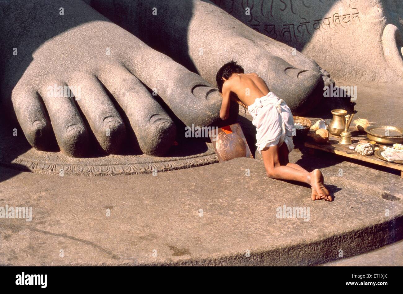 Pilgrim prostrates giant feet of Gomateshwara statue ; Gommatagiri ; Sravanabelagola ; Karnataka ; India ; Asia ; old vintage 1900s picture Stock Photo