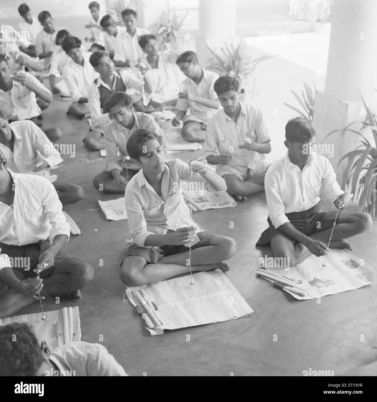 Classroom for children and adults using spindle spinning cotton into yarn ; Nanjangud ; Mysore ; Karnataka ; India ; Asia ; old vintage 1900s picture Stock Photo