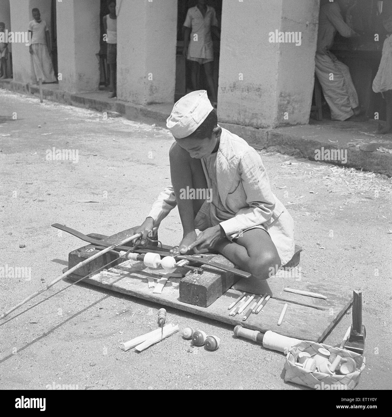 Young boy using portable rotating lathe for wood ; Channapatna ; Karnataka ; India ; Asia ; old vintage 1900s Stock Photo
