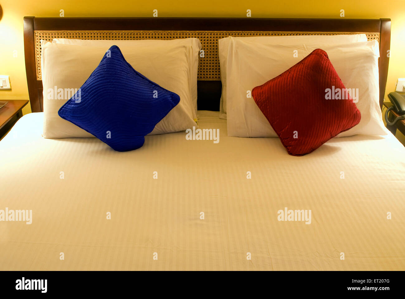 Bed with red white and blue pillows in hotel at Madikeri Coorg near Mangalore Karnataka India Stock Photo