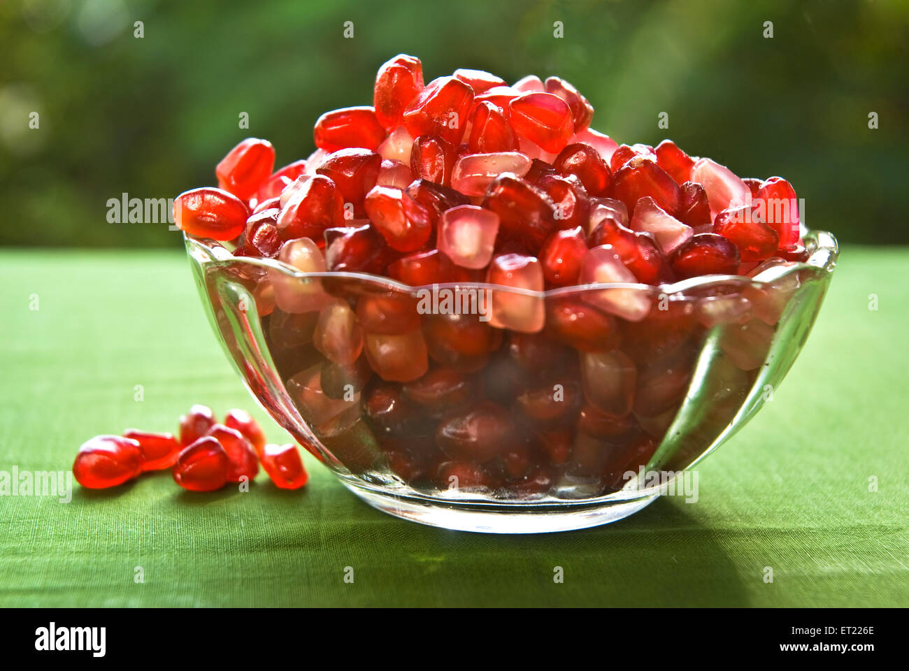 Pomegranate seeds in glass bowl on green cloth Stock Photo