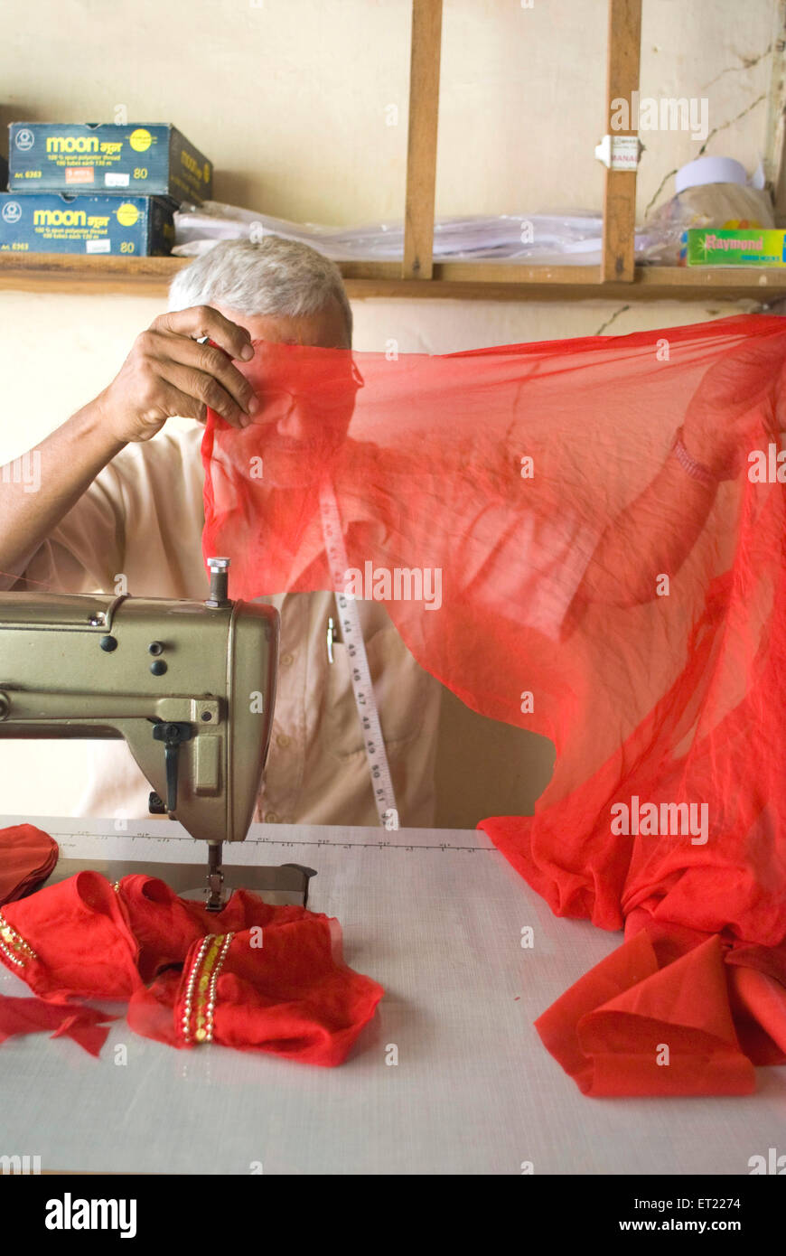 Tailor stitching red cloth on sewing machine ; Anjar ; Kutch ; Gujarat ; India Stock Photo