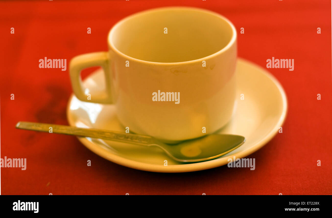 Empty white tea cup saucer spoon on red table, Panjim, Panaji, Goa, India, Asia Stock Photo