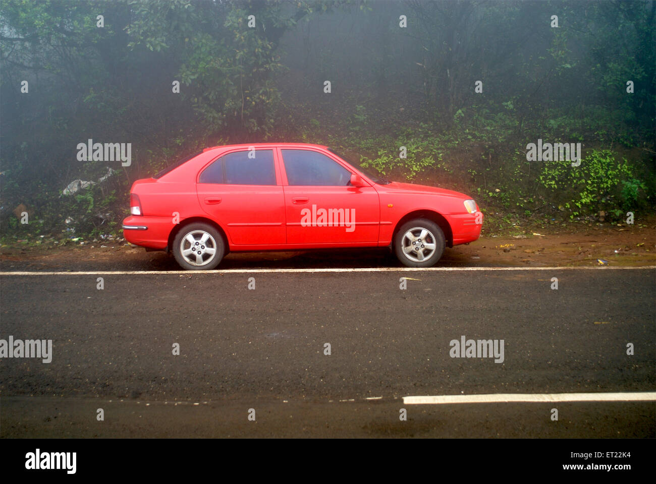 A red coloured Hyundai accent parked along the road side on a foggy day at tiger hills ; Lonavala ; Maharashtra ; India Stock Photo