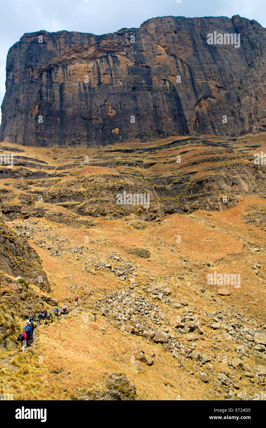 Hikers walking below Sentinel Peak in the Drakensberg Mountains Stock Photo