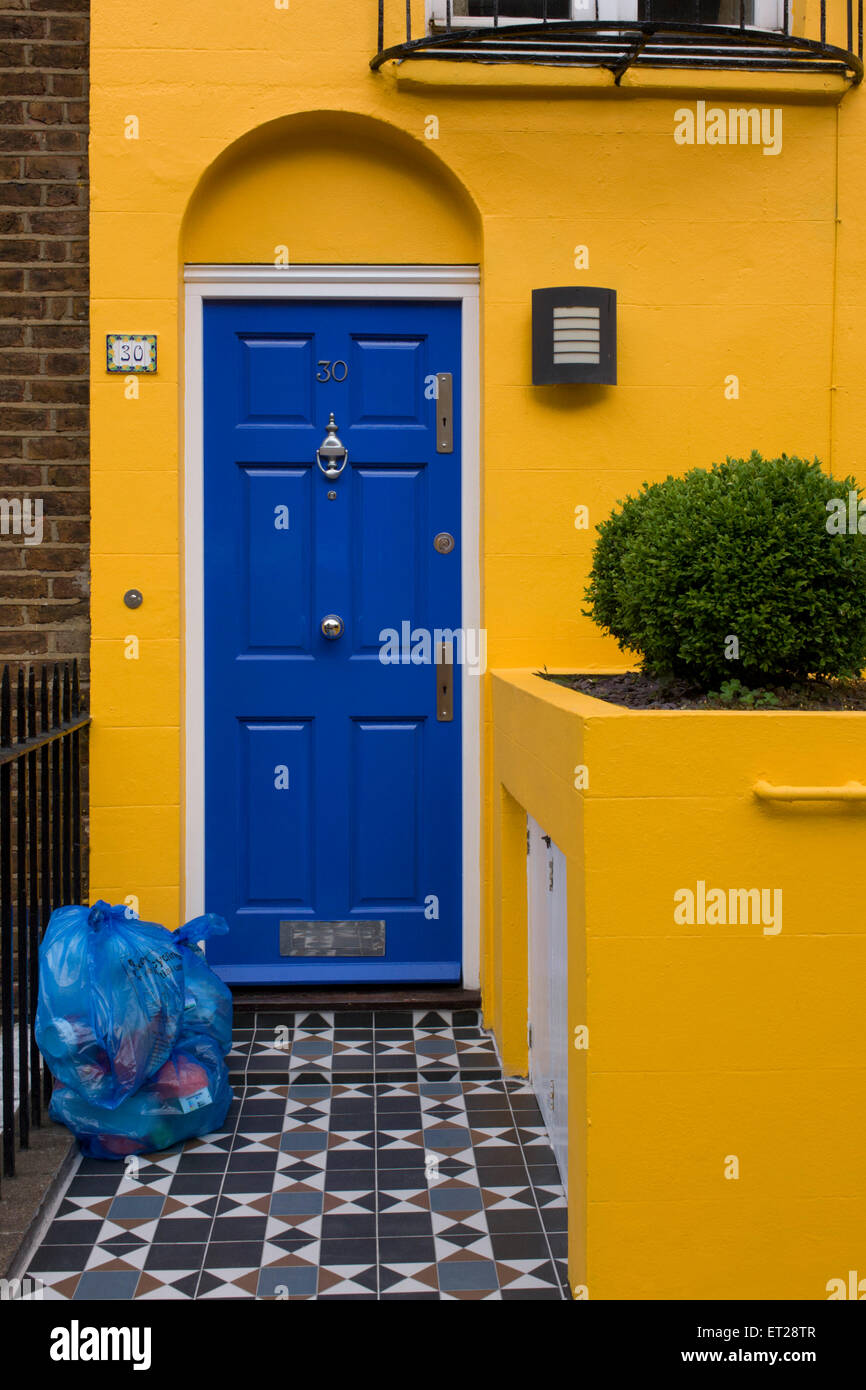 Yellow house with blue door and blue recycling bags on front doorstep